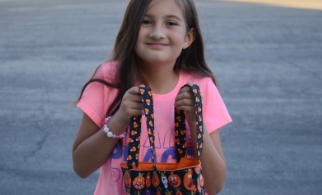 A small child holding a bag of Halloween candy.