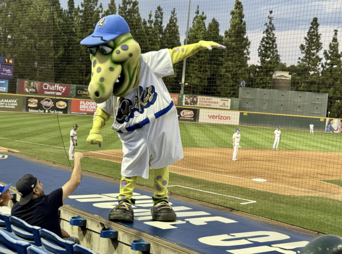 Tremor, the Rallysaurus, interacts with a fan during the first game of the final week of the Dodgers affiliation with the Rancho Cucamonga Quakes.