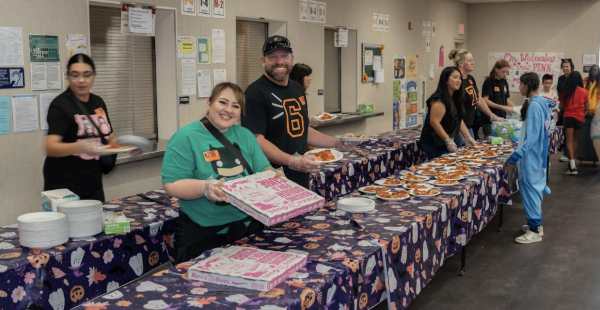 Parent volunteers serve pizza and water for the Day Creek students at the Halloween Bash.