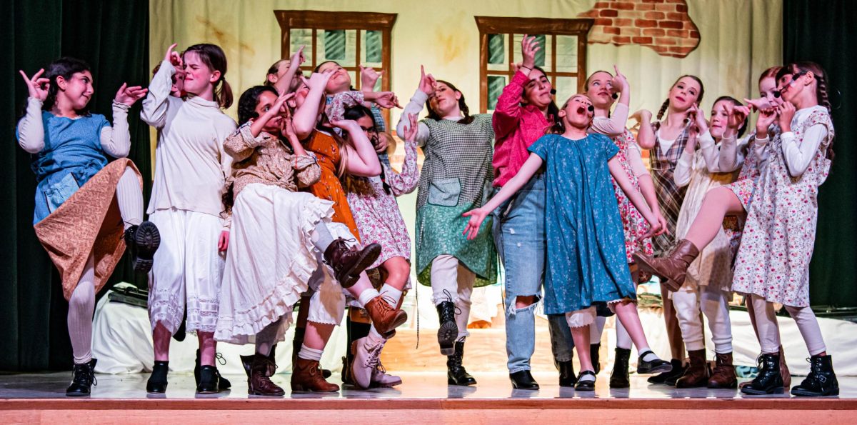 Students at Day Creek act out, singing and dancing, on stage.