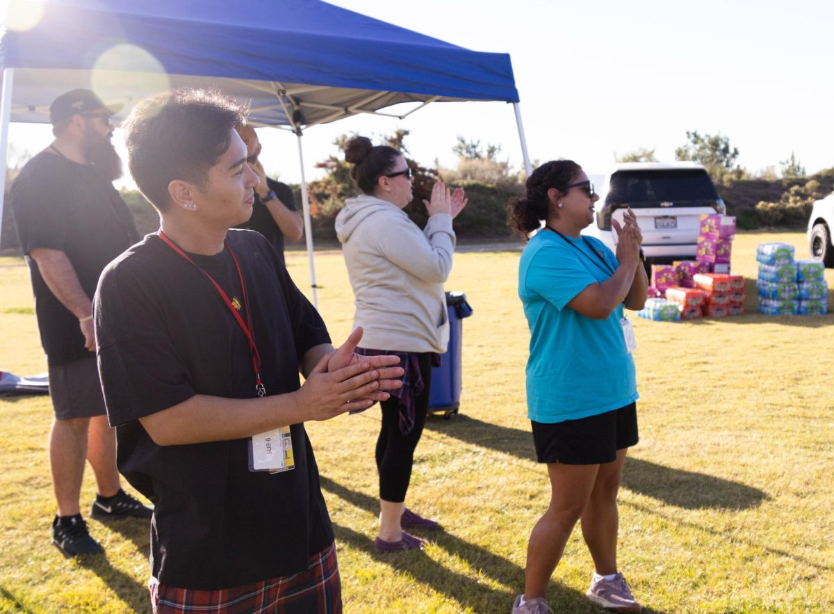 Members of the teacher team clap and cheer during the game.