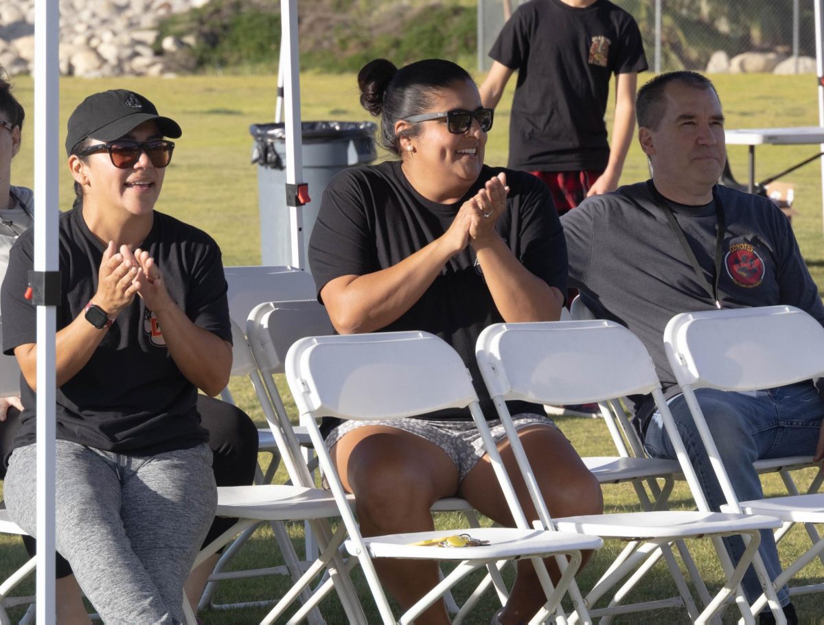Teachers watch as PE teacher Mr. Hernandez sends the ball deep into the field.