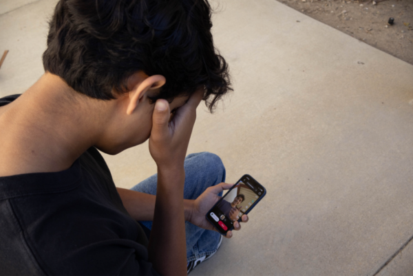 A teen stares at his phone, confronted with footage of his own behavior that has already begun circulating online.